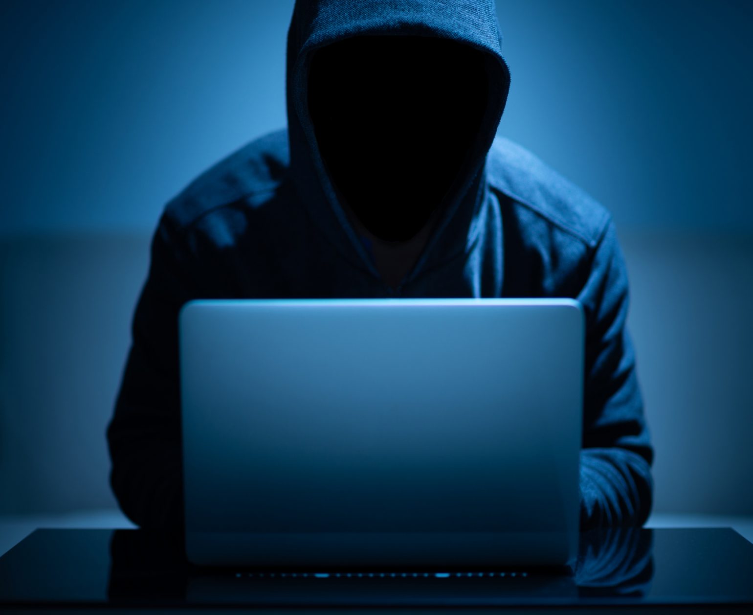 Hacker dark face using laptop