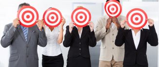 Group Of Businesspeople Holding Dartboard In Front Of Face