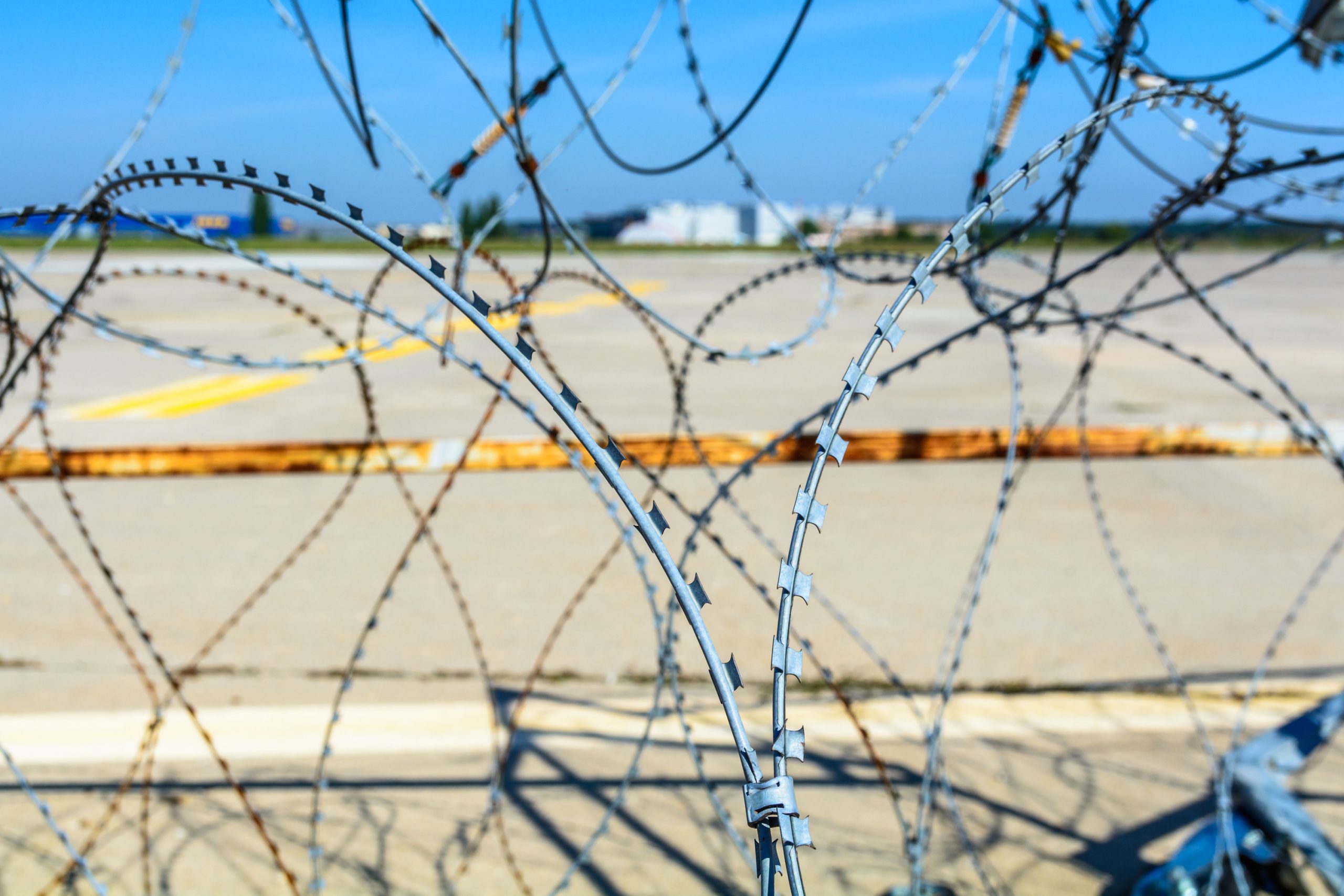 Close-up of a barbed wire fence. Horizontal view of a barbed wire fence surrounding an airport.