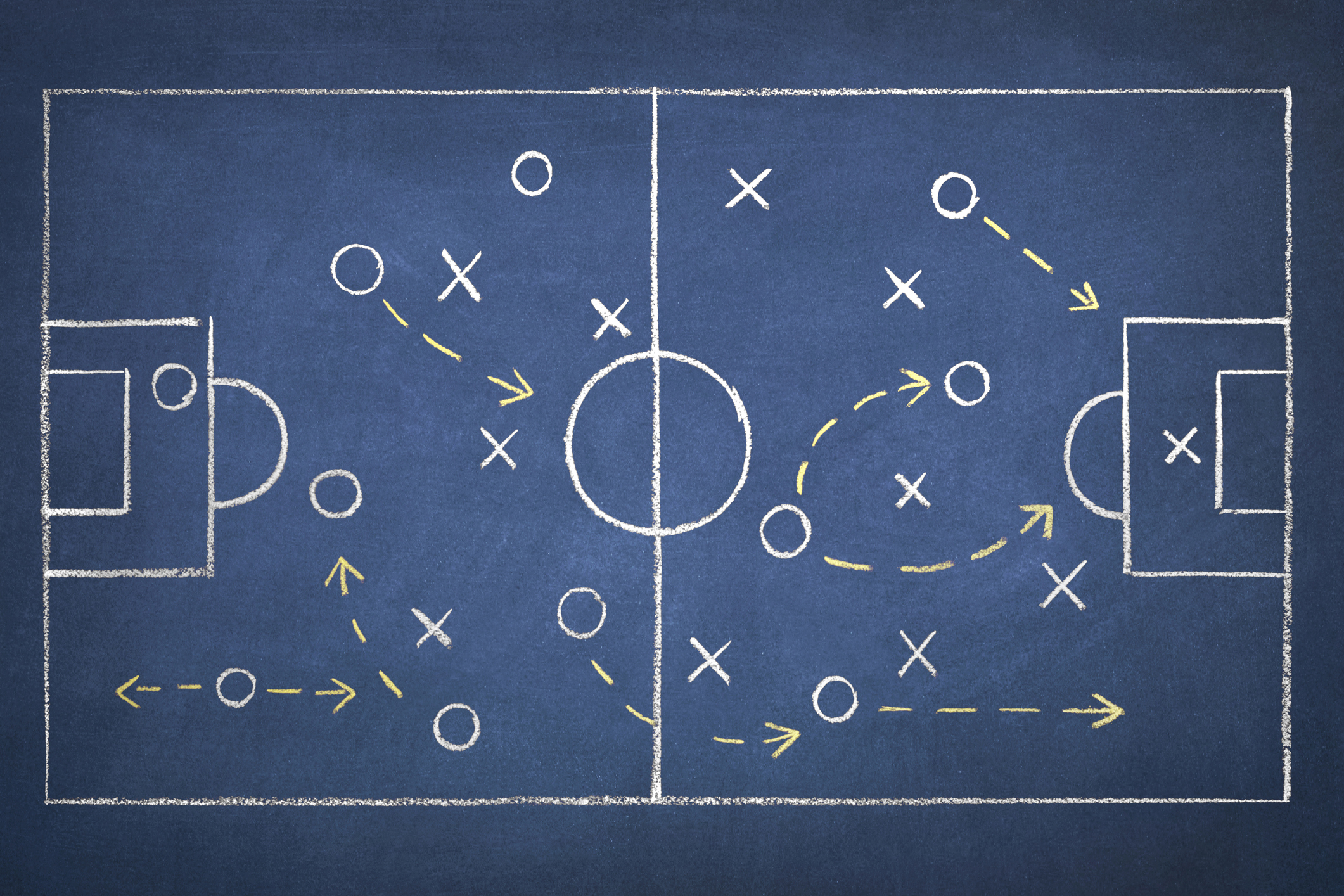 Team strategy on a chalk drawing of a soccer playing field on blue blackboard.